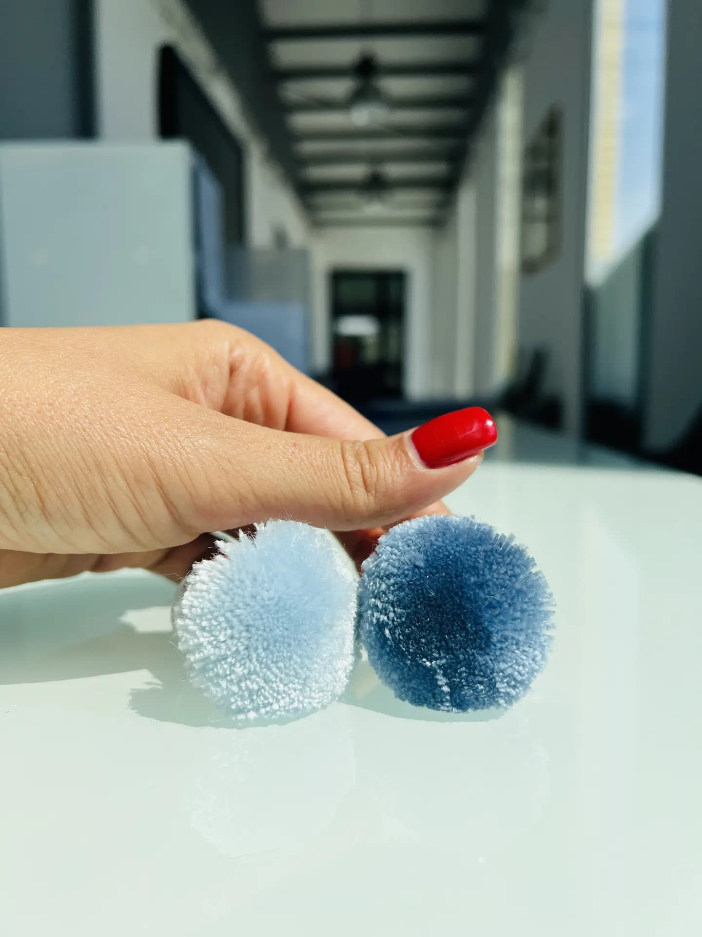 Colored yarn samples shaped as pom-poms held in a hand