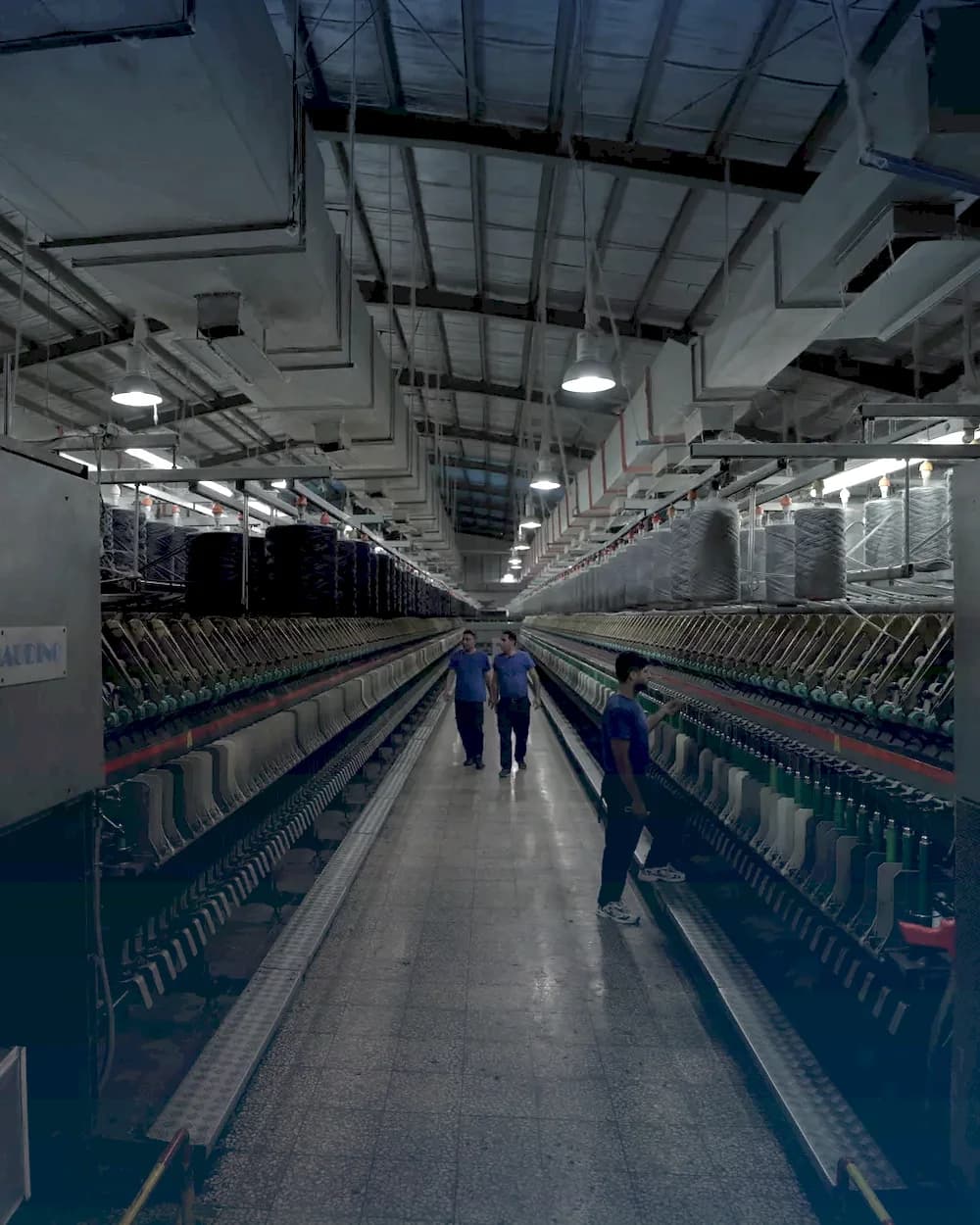 The Bayer Kashan spinning hall with rows of machines and yarn cones